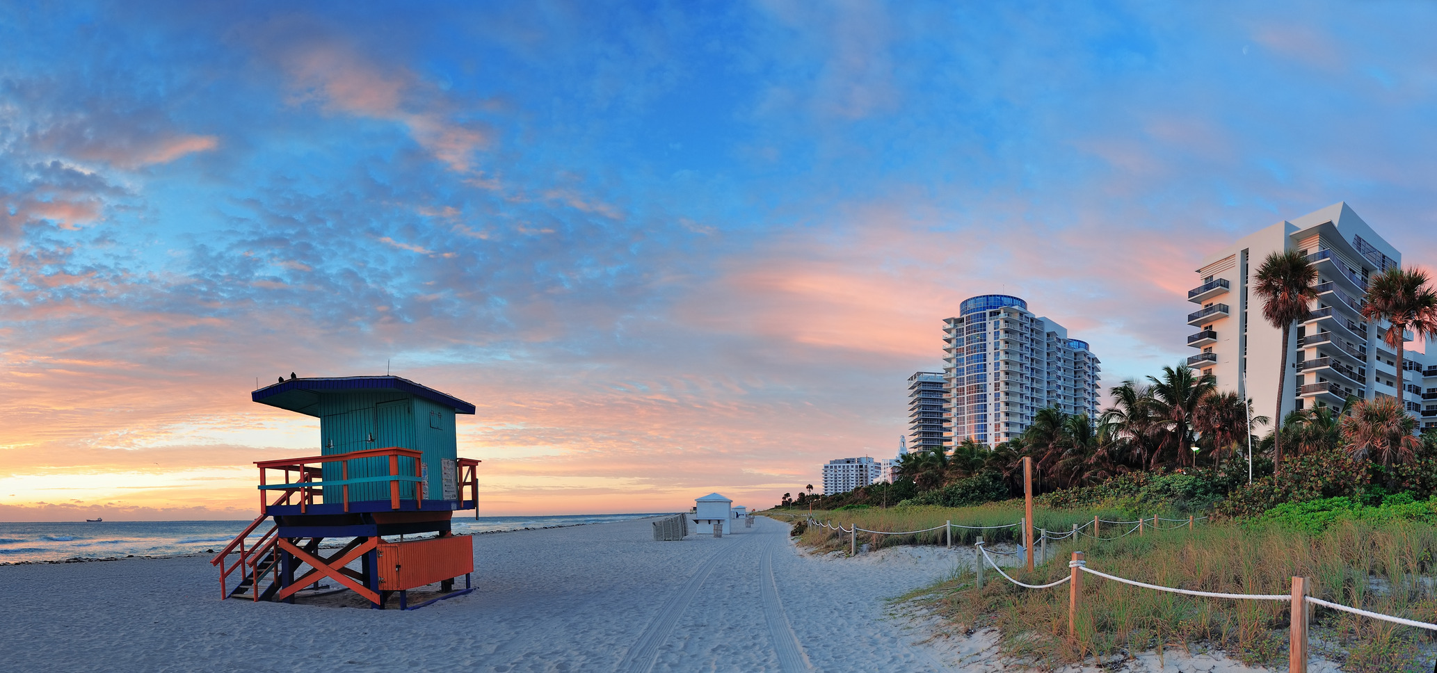 Miami South Beach sunrise with hotels and coastline with colorful cloud and blue sky.